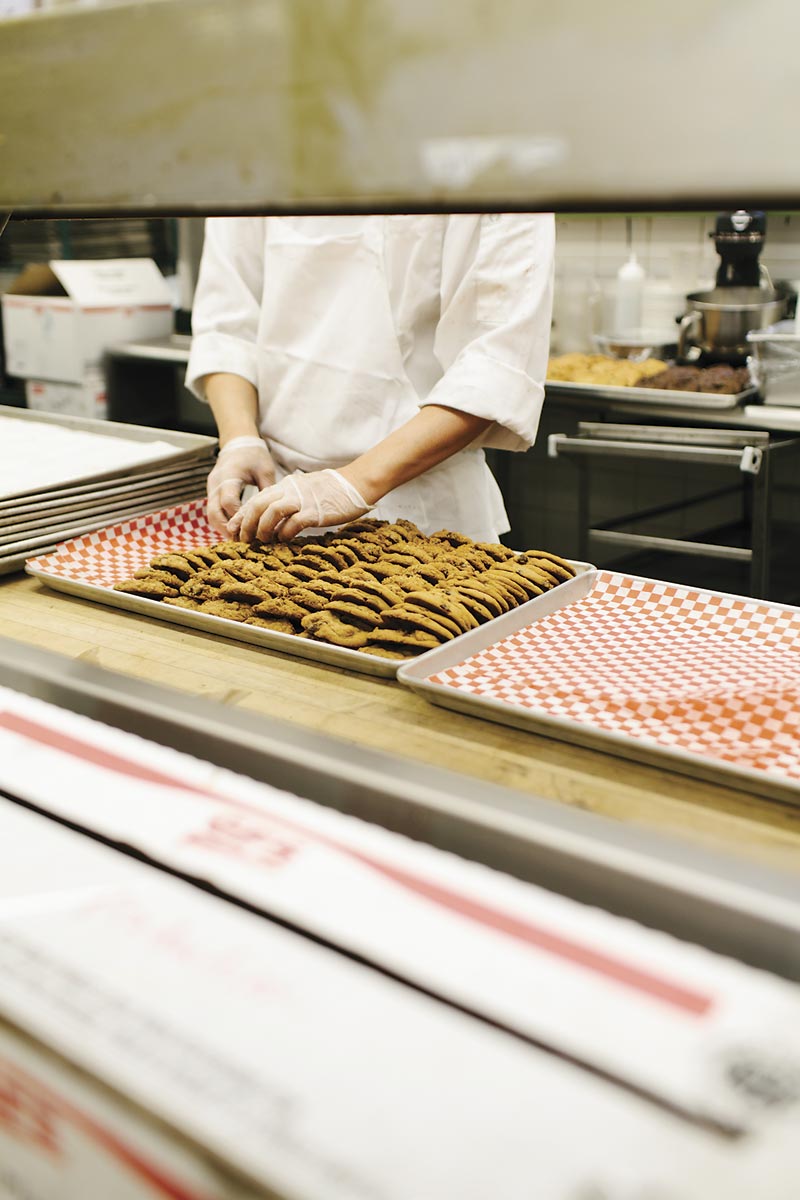 A hand laying out cookies on a tray.